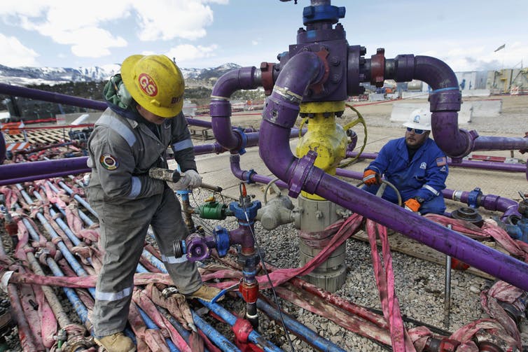 Workers tend to a well head during a hydraulic fracturing operation