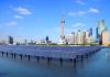 A picture of Beijing's skyline with a field of solar panels propped up in the water before it 