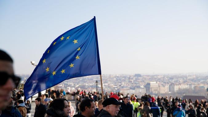 A crowd with a person holding an EU flag