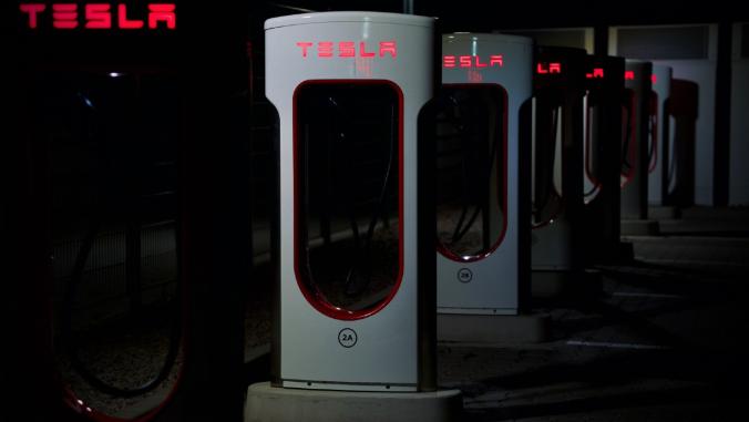 A row of Tesla chargers in the dark.